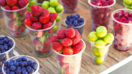 Juicy fruits and berries in plastic cups, perfect for a hot day refreshment
