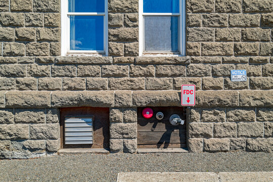 FDC sign points to the fire department connections for a sprinkler system on the outer wall of an old stone building