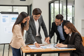 Group of Asian businessmen are presenting graphs on a whiteboard.
