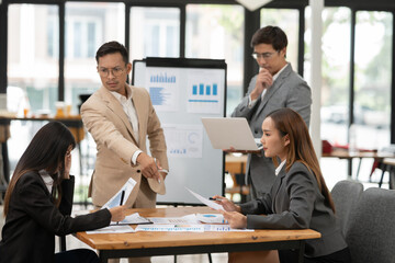 Asian business group discussing graph work at the office..