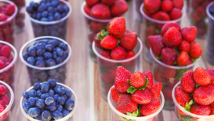 Juicy fruits and berries in plastic cups, perfect for a hot day refreshment