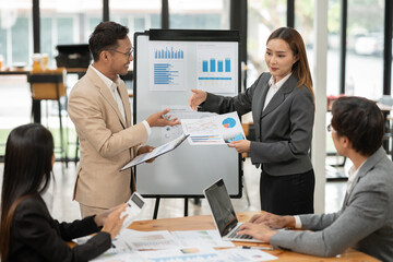 Group of Asian businessmen are presenting graphs on a whiteboard.
