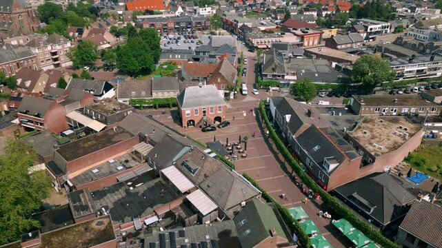 Drone view above Budel city centre, capturing Markt central square in this rural Brabant village. Footage showcases the heart of the village, highlighting buildings and streets. Location: Budel