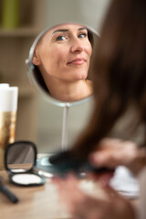 happy woman cleaning face in bathroom mirror