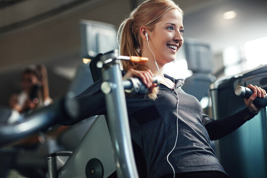 Gym, woman and smile on chest press machine for workout to exercise for health, fitness and muscles. Female person, happy and earphones with training for wellbeing, wellness and self care in routine