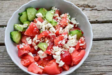 Traditional Bulgarian shopska salad with  tomatoes ,cucumbers and cheese on wooden board