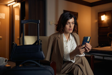Young businesswoman typing message on smartphone booking return ticket