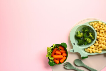 Colorful kids meal featuring vegetables and pasta on green plates on pink background