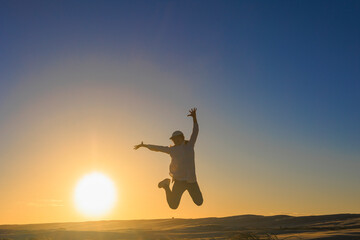 夕暮れ、ジャンプする女のシルエット