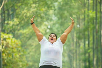 Picture of excited fat woman wearing sportswear in a park