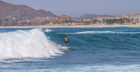 in the waves of the capes, in the background the hotel zone during the summer vacation season, with visitors from all over the world. Cabo San Lucas, Baja MEXICO
