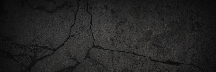 Texture of old cracked concrete wall. Rough dark gray concrete surface with spots, cracks, noise and grain. Dark wide panoramic background for design. Shaded texture with vignette.