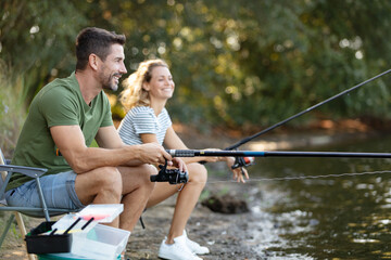 man and woman fishing from the river-bank