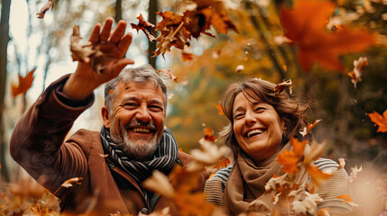 Elderly couple throwing leaves fun in a forest on an autumn day