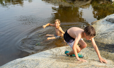 Two Caucasian boys 8 years old playing in a river in summer