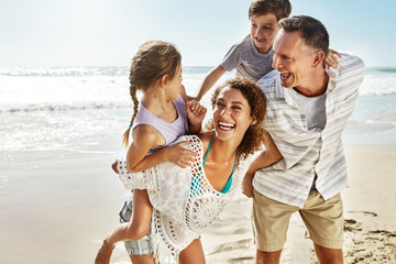 Happy family, laughing and piggyback at beach in summer for relax, travel and holiday in Miami. Parents, children and people at ocean with back ride for trust, vacation and bonding together by water