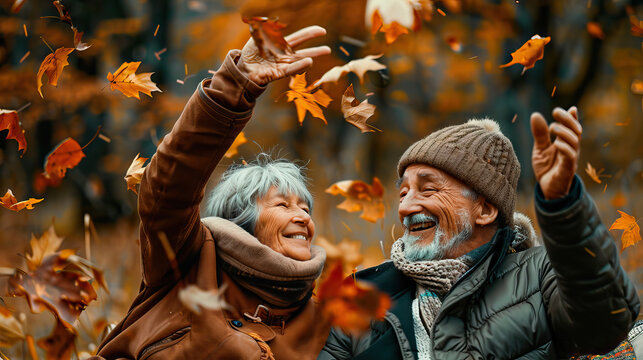 Elderly couple throwing leaves fun in a forest on an autumn day - Powered by Adobe