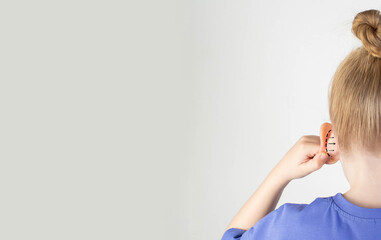 The girl holds her hand on her protruding protruding ear with marks for plastic surgery. Changes in...