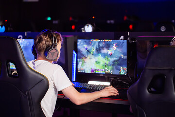 Caucasian teen gamer in headset playing PC video game at computer club. E-sport championship tournament, cyber sport team. Multiplayer online real-time strategy RTS, PvP battle competition