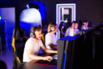Obraz premium Team of gamers playing video game on PC at computer club, cyber sport tournament. E-sport championship. 5 players in headset communicate with each other over mic. Multiplayer online competition blurry