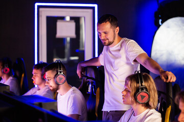 E-sport coach is watching trainer comments gives instructions to his players. Gamers in headset play video game on PC at computer club in tournament cyber sport team. Tactics strategy emotions Closeup © HENADZY
