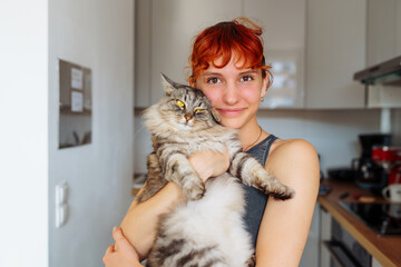 portrait red-haired teenage girl with gray fluffy cat