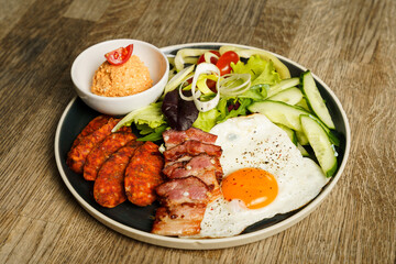 Breakfast with bacon, fried eggs, sausage and salad