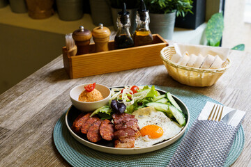 Breakfast with bacon, fried eggs, sausage and salad