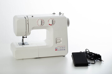 Automatic modern sewing machine with overlock and black pedal on a white background, isolate. Studio concept. Tailoring services, close-up
