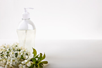 Mockup. Transparent hand soap dispenser surrounded by fresh spring blossoms on white background, portraying hygiene and nature's touch. Shampoo, shower gel, body lotion. Natural organic cosmetics