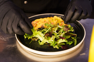 Preparing scrambled eggs with salad and tomato