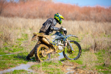 A motorcyclist rides an enduro motorcycle off-road. Driving through swampy areas, water and mud...