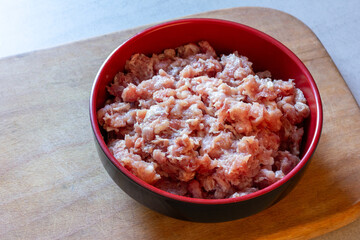 minced pork in a bowl on a wooden chopping board on a table close-up