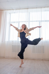 Caucasian woman dances contemporary in ballet class. Dancer in a jump. Vertical photo.