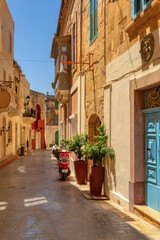 Narrow, winding alleyway in Victoria ancient core reveals historic sandstone facades and glimpses of Malta's storied past. Gozo, Cultural heritage of Malta,