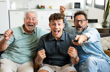 Enthusiastic three generation men family fans watch football championship or olympic games on TV...