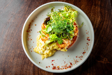 A gourmet dish featuring shrimp and greens atop a creamy base, served on an oval plate—a perfect fit for culinary themes