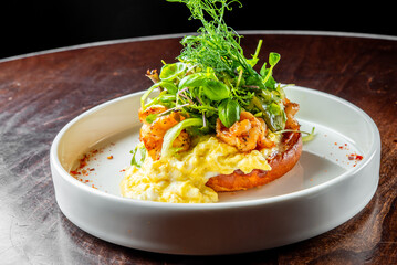 A gourmet dish featuring shrimp and greens atop a creamy base, served on an oval plate—a perfect fit for culinary themes