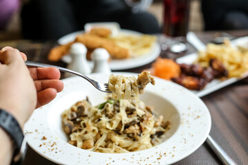 Person Holding Fork Over Bowl of Pasta