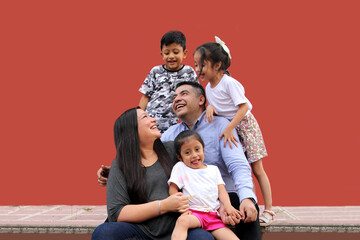 Family of dark-skinned Latino mom, dad, son and daughters looking happy and healthy celebrating their day