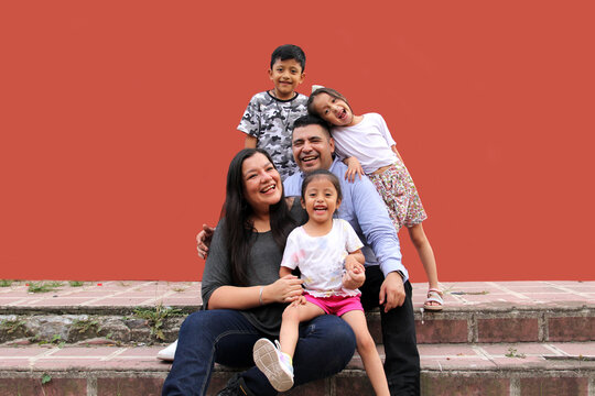 Family of dark-skinned Latino mom, dad, son and daughters looking happy and healthy celebrating their day