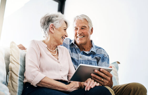 Mature couple, browsing and tablet in living room in house with online funny movie streaming on website. Laughing, subscription and people in home with networking, social media and app in retirement.
