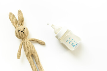 Feeding time - milk for baby in bottle with bunny toy, top view