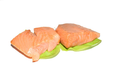 The picture shows pieces of salmon lying on lettuce leaves. The fish is ready to eat.