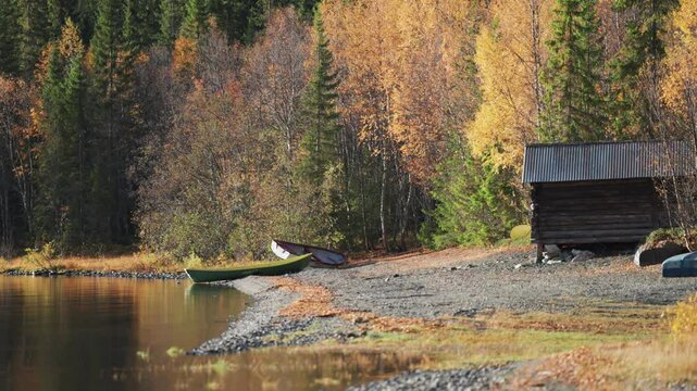 Serene shores of an autumn forest, where two boats lay peacefully on a pebble beach, amidst the vibrant hues of fall foliage