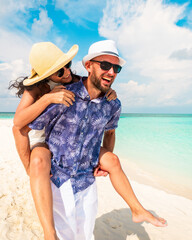 Couple in love tropical beach with turquoise ocean and sunshine .Maldives island. Having fun man carry woman on his back.Romantic holidays vacation. Just married get away holidays