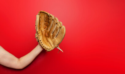 Baseball glove on woman's hand. Red background, copy space. Active sport, championship, victory.