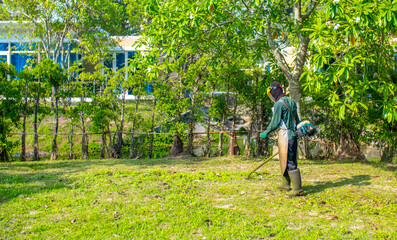 A worker mows the lawn with a manual lawn mower on the hotel grounds. Mowing the garden meadow lawn. Summer work in the garden.