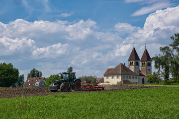 Insel Reichenau, Traktor pflügt vor der Kirche St. Peter und Paul © Peter Allgaier