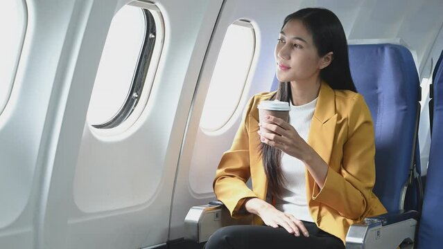 Young Asian executive excels in first class, multitasking with digital tablet, laptop and smartphone. Travel in style, work